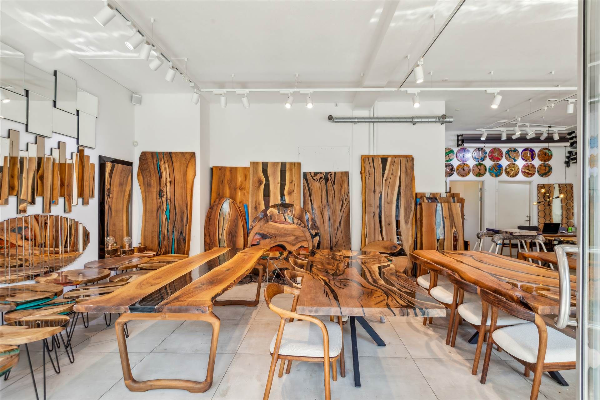 Showroom med store træborde, stole og kunstværker på væggen, alle i naturlige farver og materialer