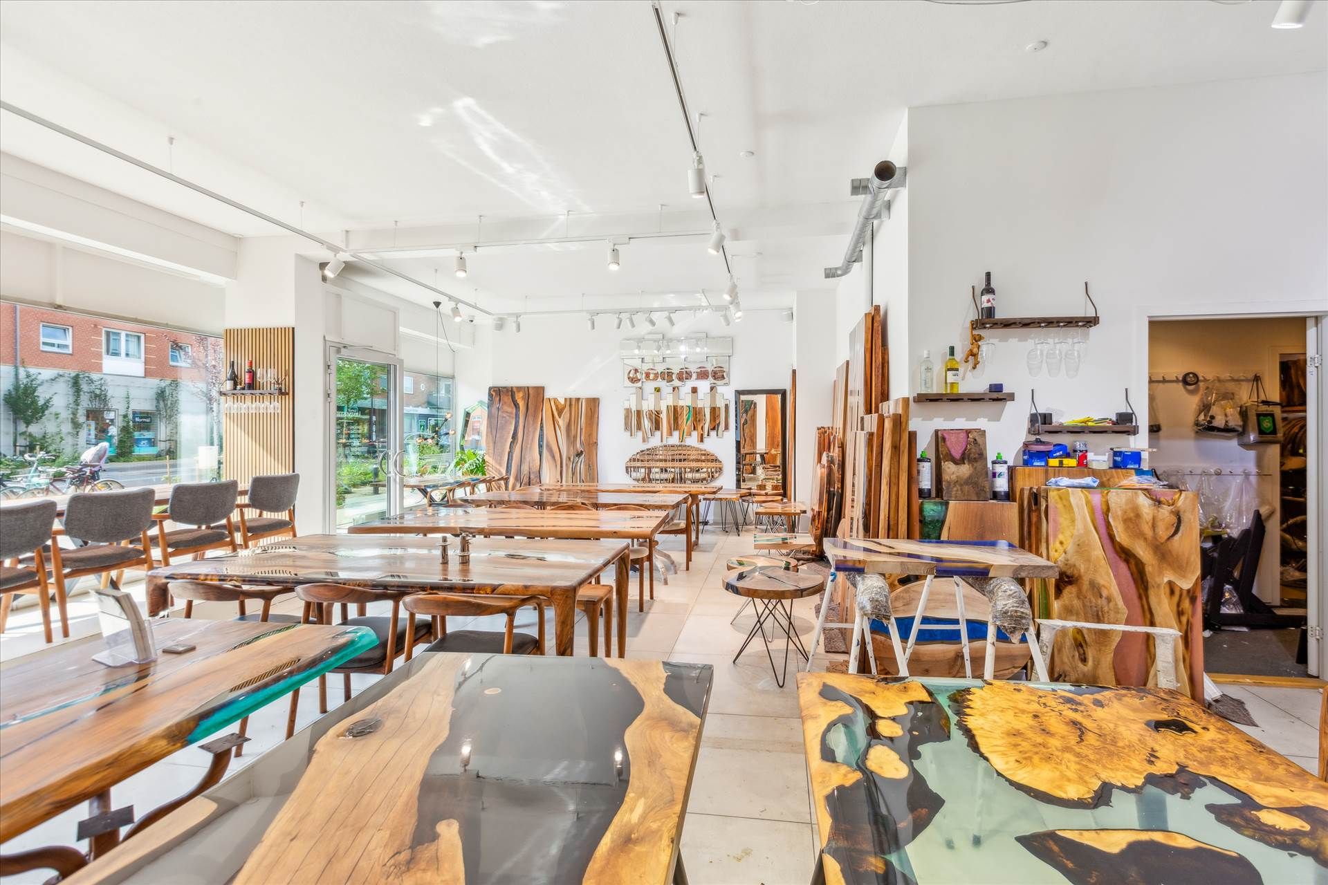 Vinduesfyldt showroom med lyse lofter og højtidligere møbler og skriveborde i træ og glas. Lysstofrør og naturligt lys.