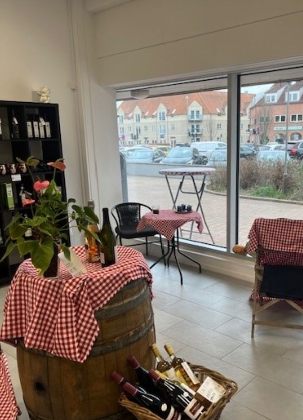 Inde i et vinbutik er der en vinfat, en vase med blomster, en rund bord med en stol og en rundt bord med en flaske og en