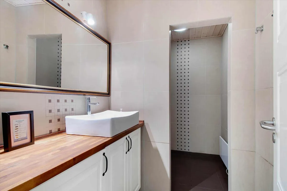 Et elegant hvidt badeværelse med moderne design, hvor en hvid vask med en bøjle er placeret i midten, og en indbygget