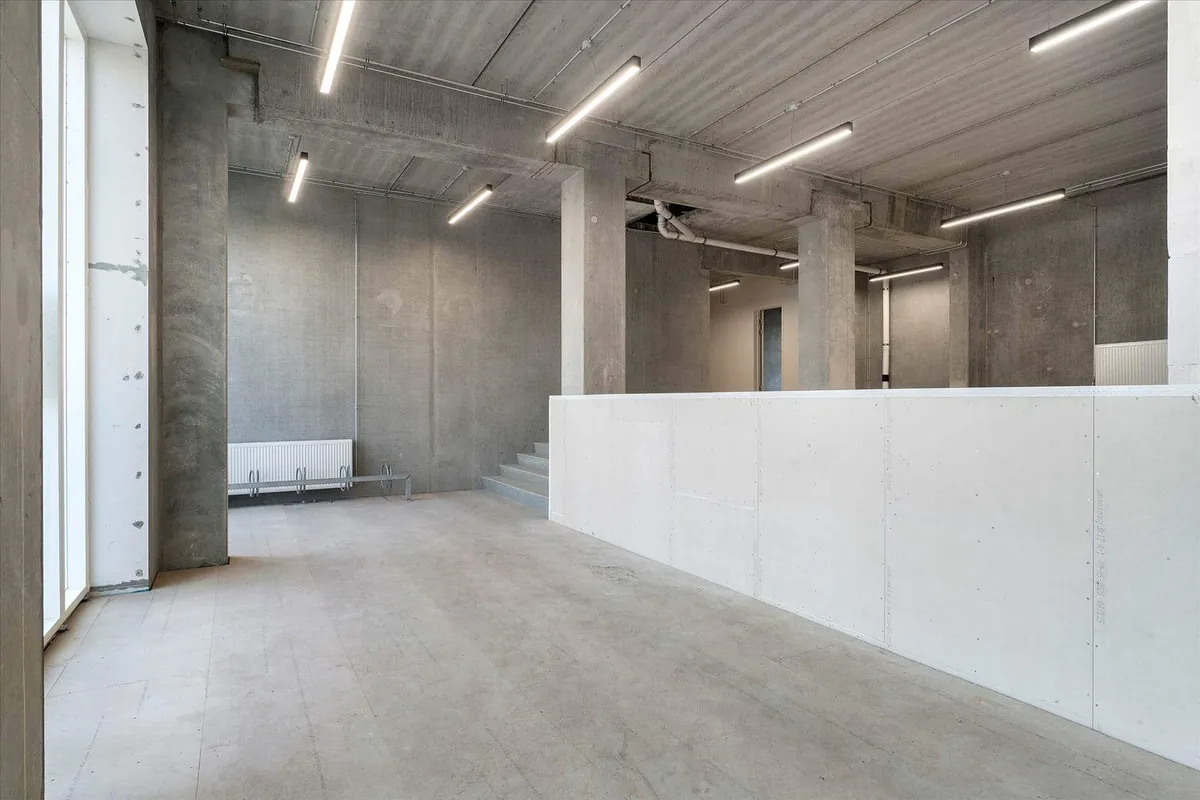 En stor hall med cementgulve og loft, hvor der er flere lysekroner og en hvid mur.