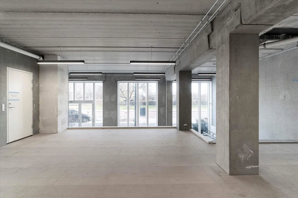 Moderne erhvervslokaler med hvide vinduer og store glasdøre samt beton og hvid maling i væggene og loftet