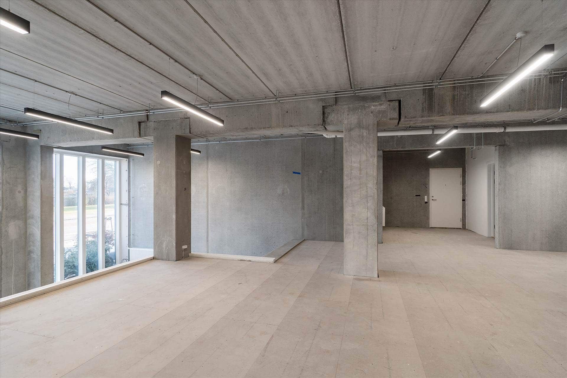 Ulejet erhvervslokal med store vinduer og højloft, tæt ved Amager Strandpark. Værelset er i øjeblikket tomt og har lysgrå