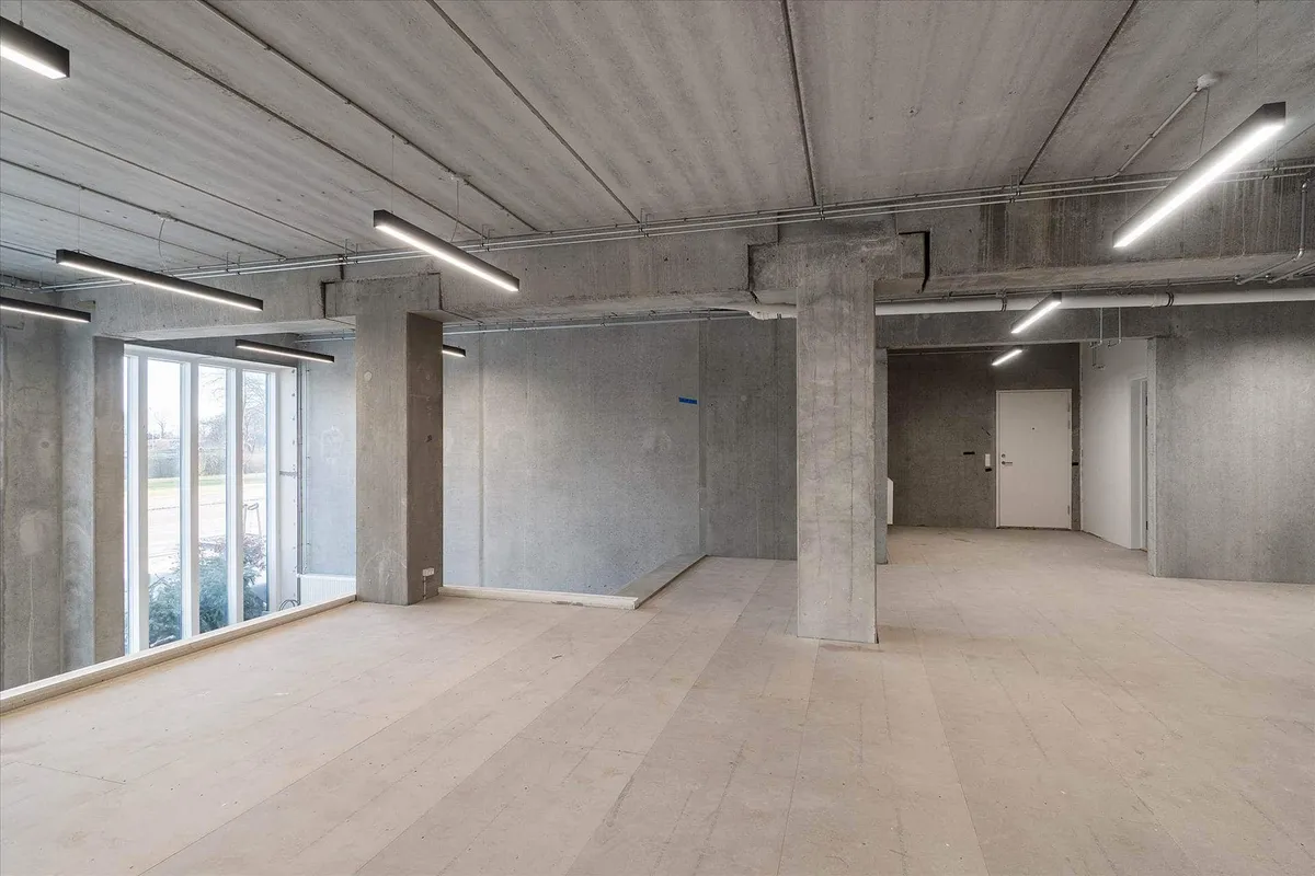 Ulejet erhvervslokal med store vinduer og højloft, tæt ved Amager Strandpark. Værelset er i øjeblikket tomt og har lysgrå