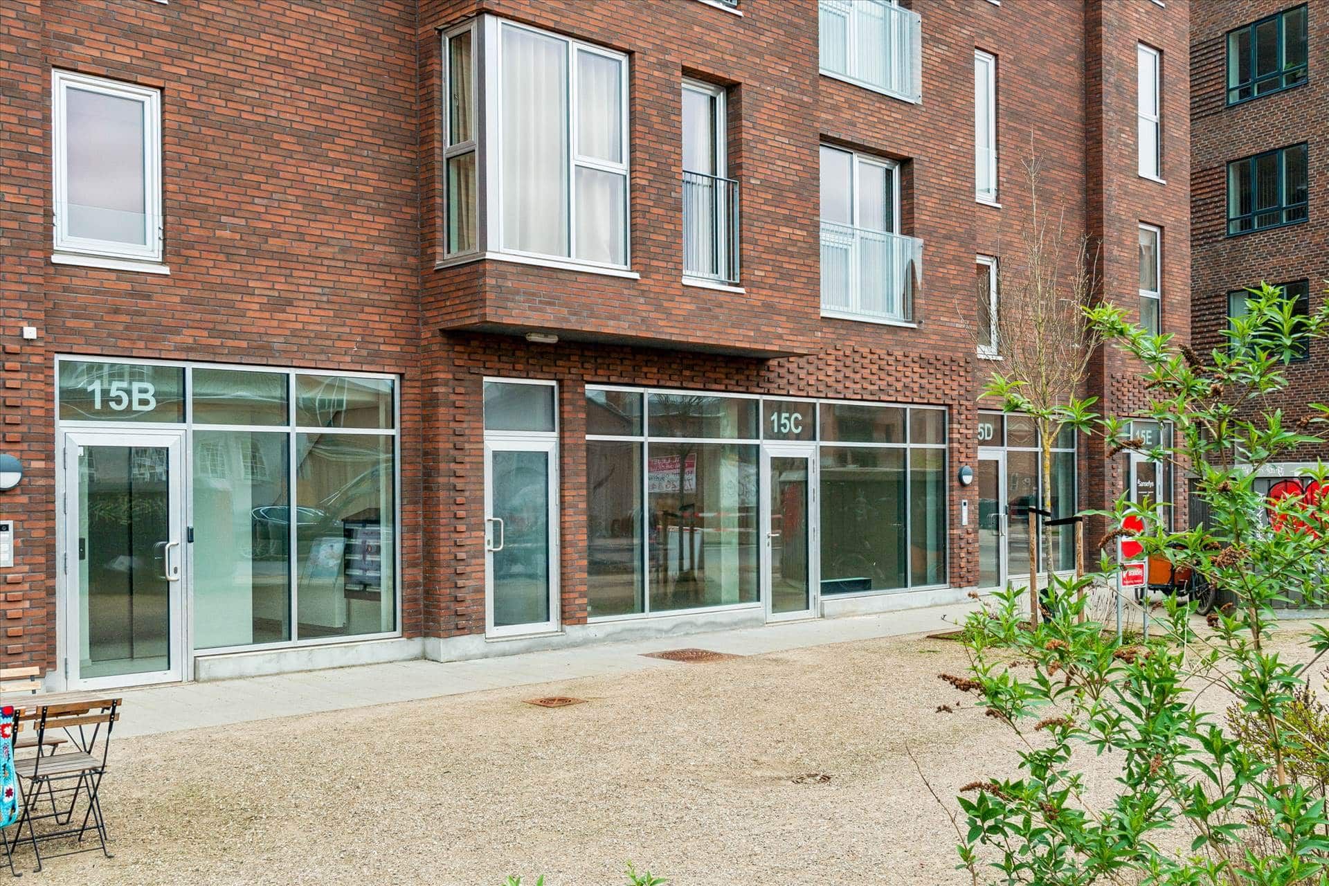Foto af et lejlighedskompleks med røde mursten og glasvinduer i Forfatterkvarteret med nummer 15B og 15C