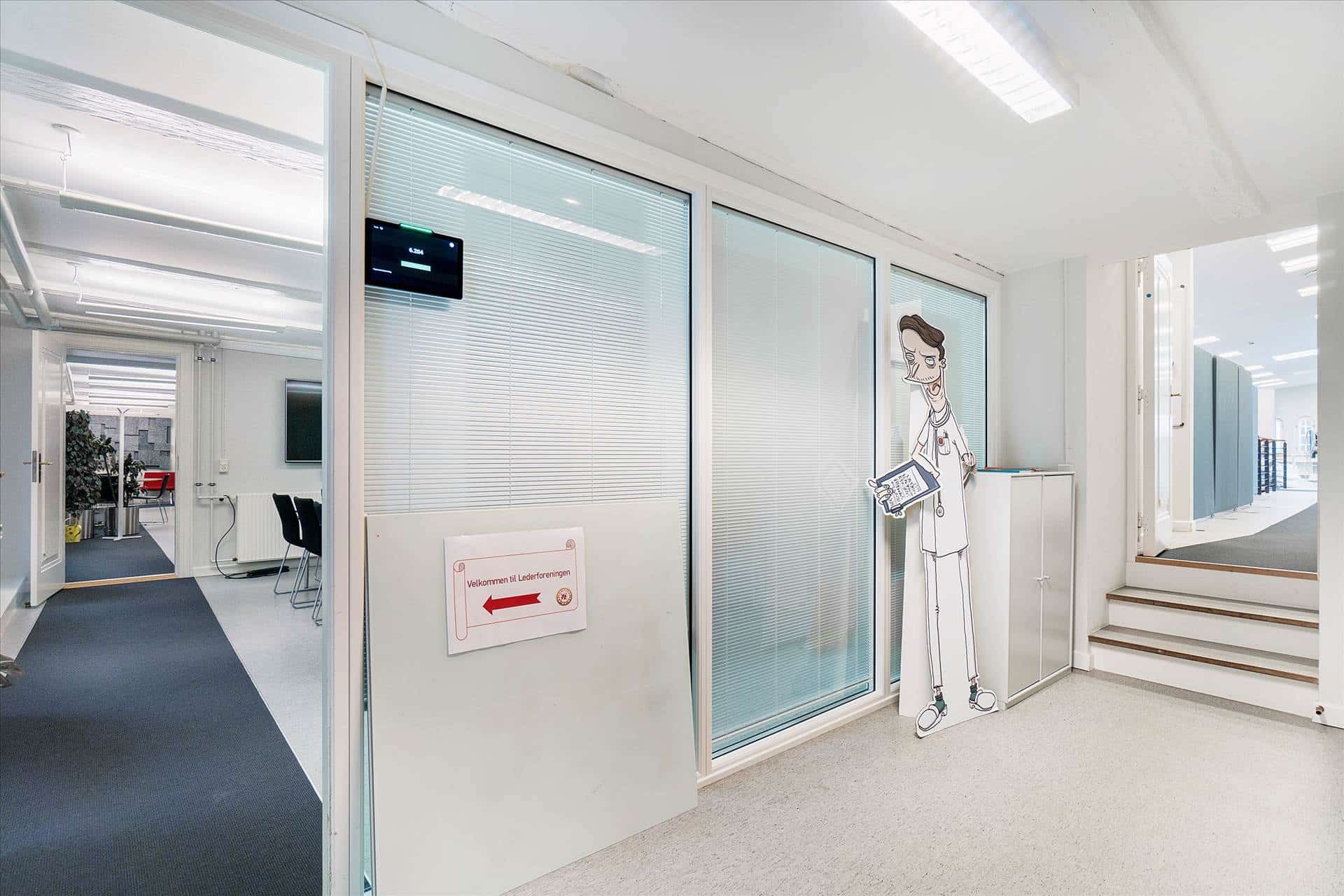 Indkørslet til kontorbygning med hvid væg og blå gulv. Styret gulv med skrift og illustration på væggen. Værelse med