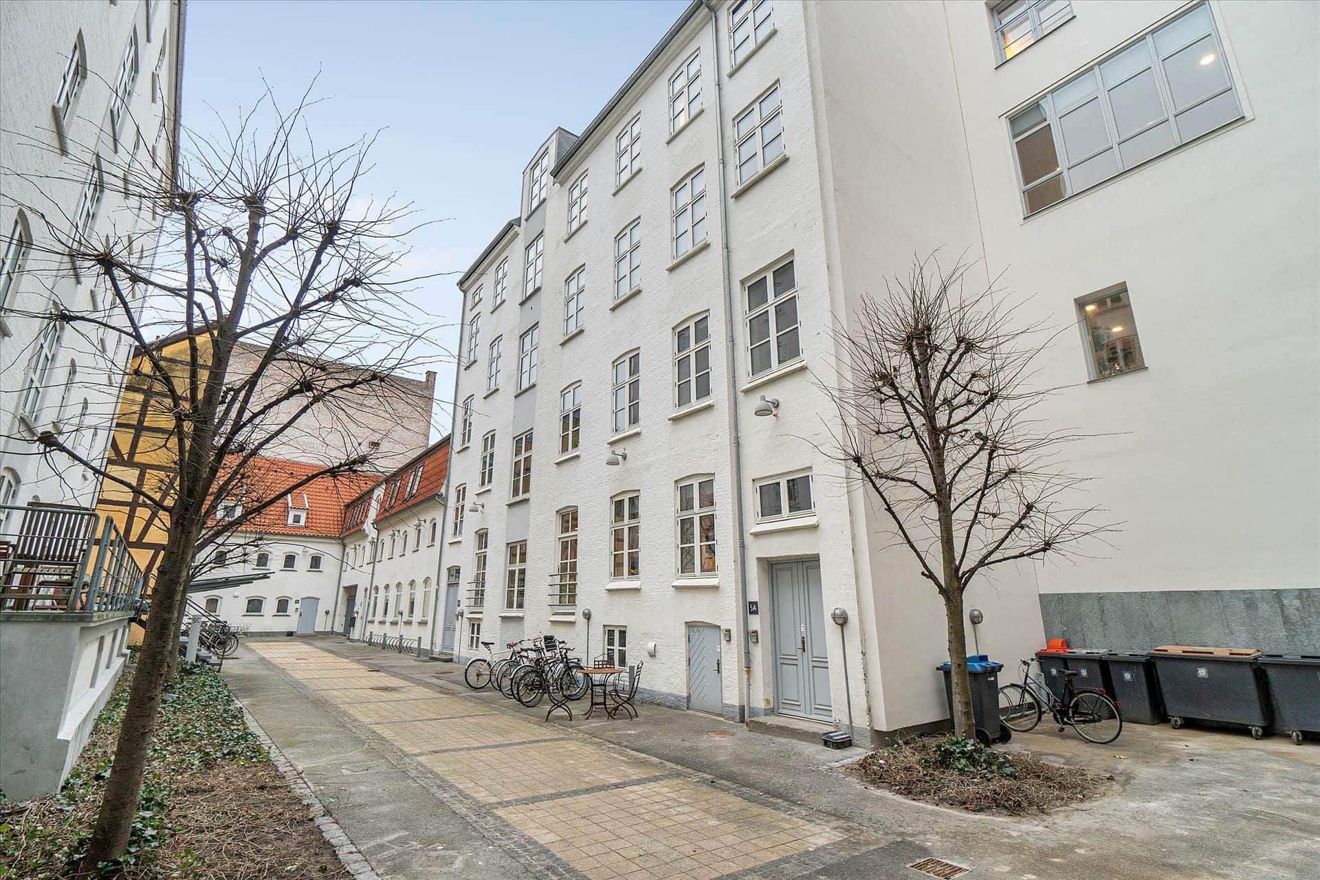 Dejligt kontor i flot gårdhus med en række cykler parkeret udenfor og slanke træer i gårdhaven