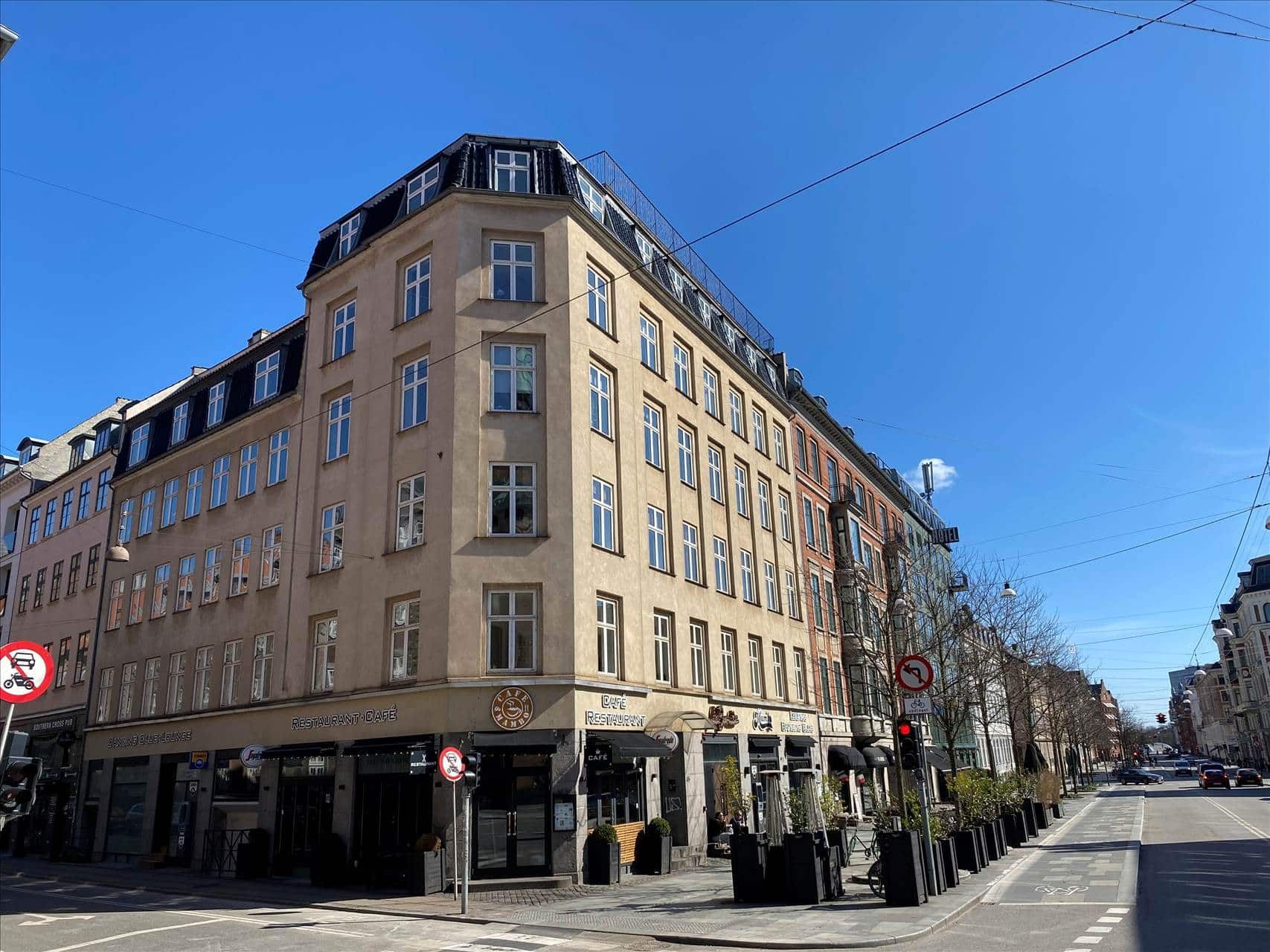 Lys og nytindrettet kontorlokal med elevator og udsigt over byens tage. Bygningen er i lysebrunt og har flere vinduer og