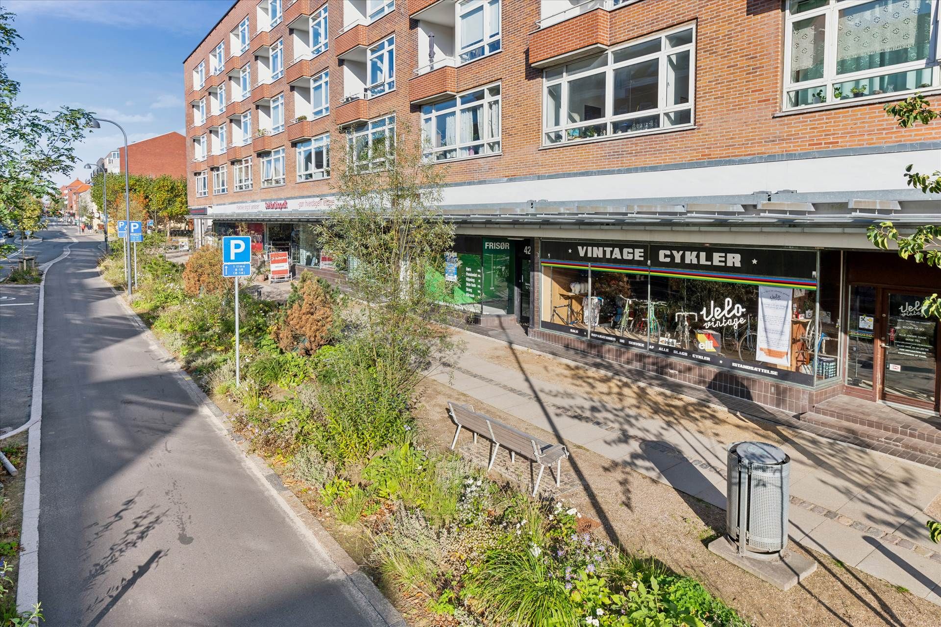 Vintage Cykler forretning ligger på Søborg Hovedgade, med plantager, parkeringsskilte og søjler på fortovet