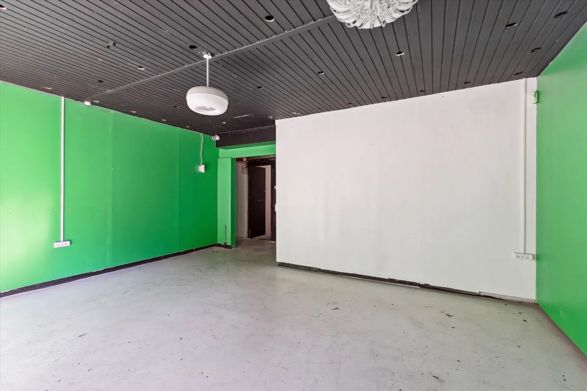 Store tomt lokale med hvide og grønne vægge og lysekroner hængende fra loftet, der er udstyret med ventiler og ledningsforløb