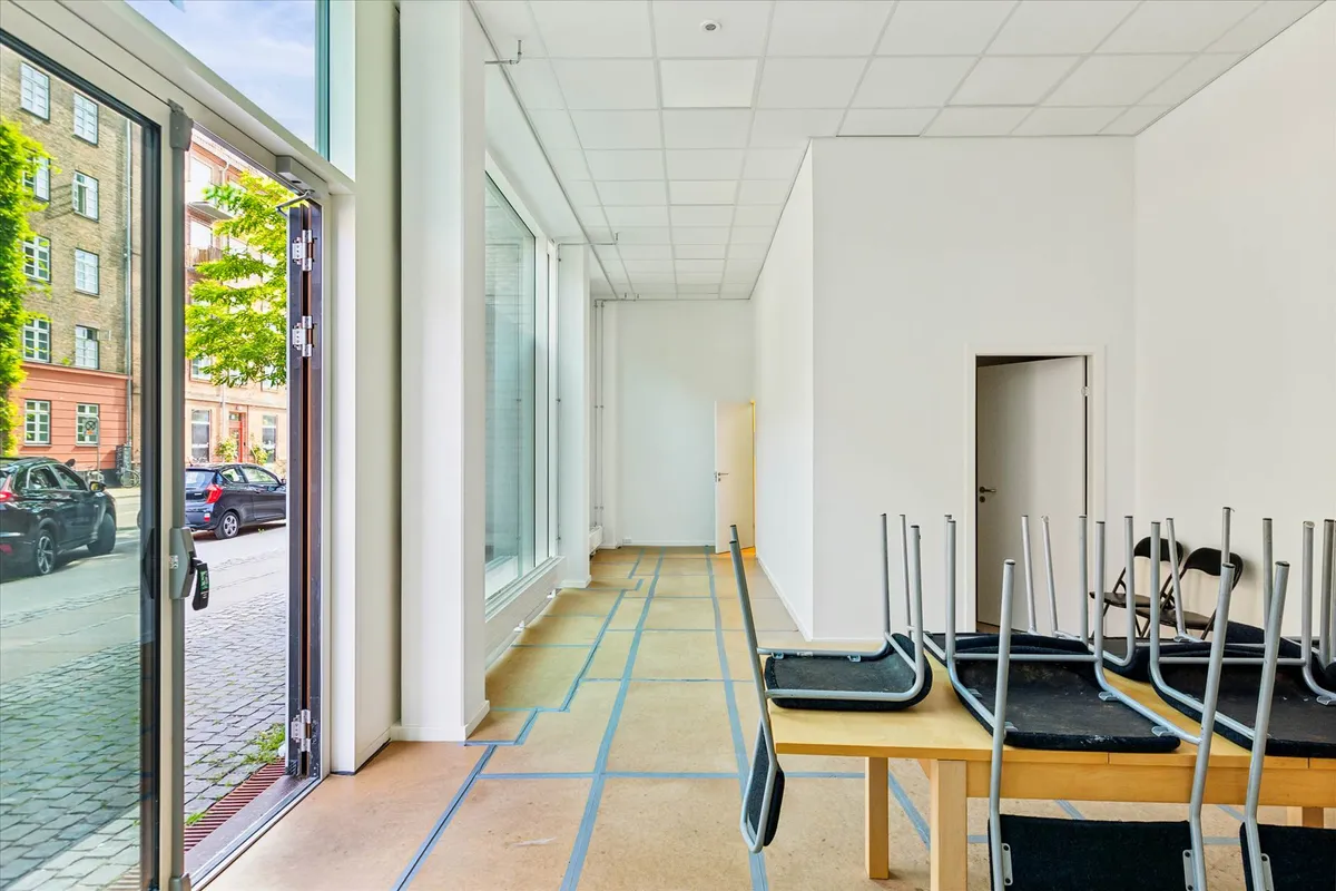 Moderne og rent kontorlokaler med hvide vægge og højt til loftet og fuldstændig nye gulve. Værelset er tomt med stolpebord