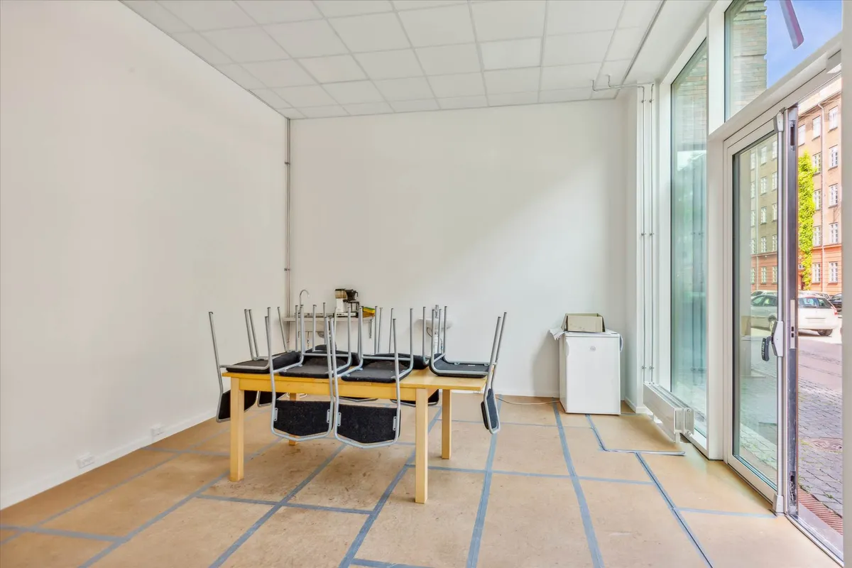 Værelse med lyse lofter og hvide vægge med to stole samt en bord. Værelset er tomt og uden møbler.