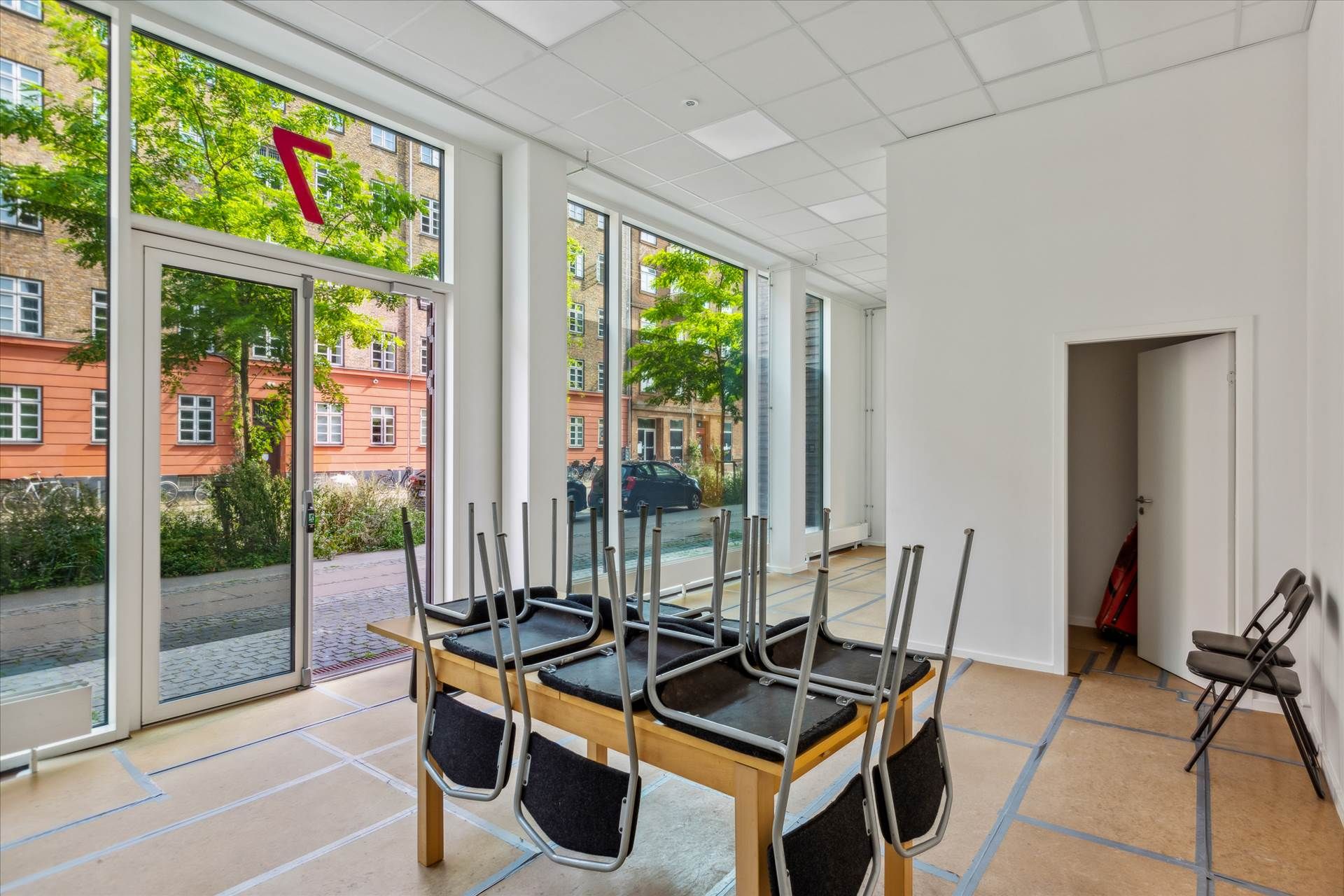 Lige til salg nyt butikslokal med store glasvinduer og indvendige vægge i hvidt og brunt. Gulvet er i brun farve og møblerne