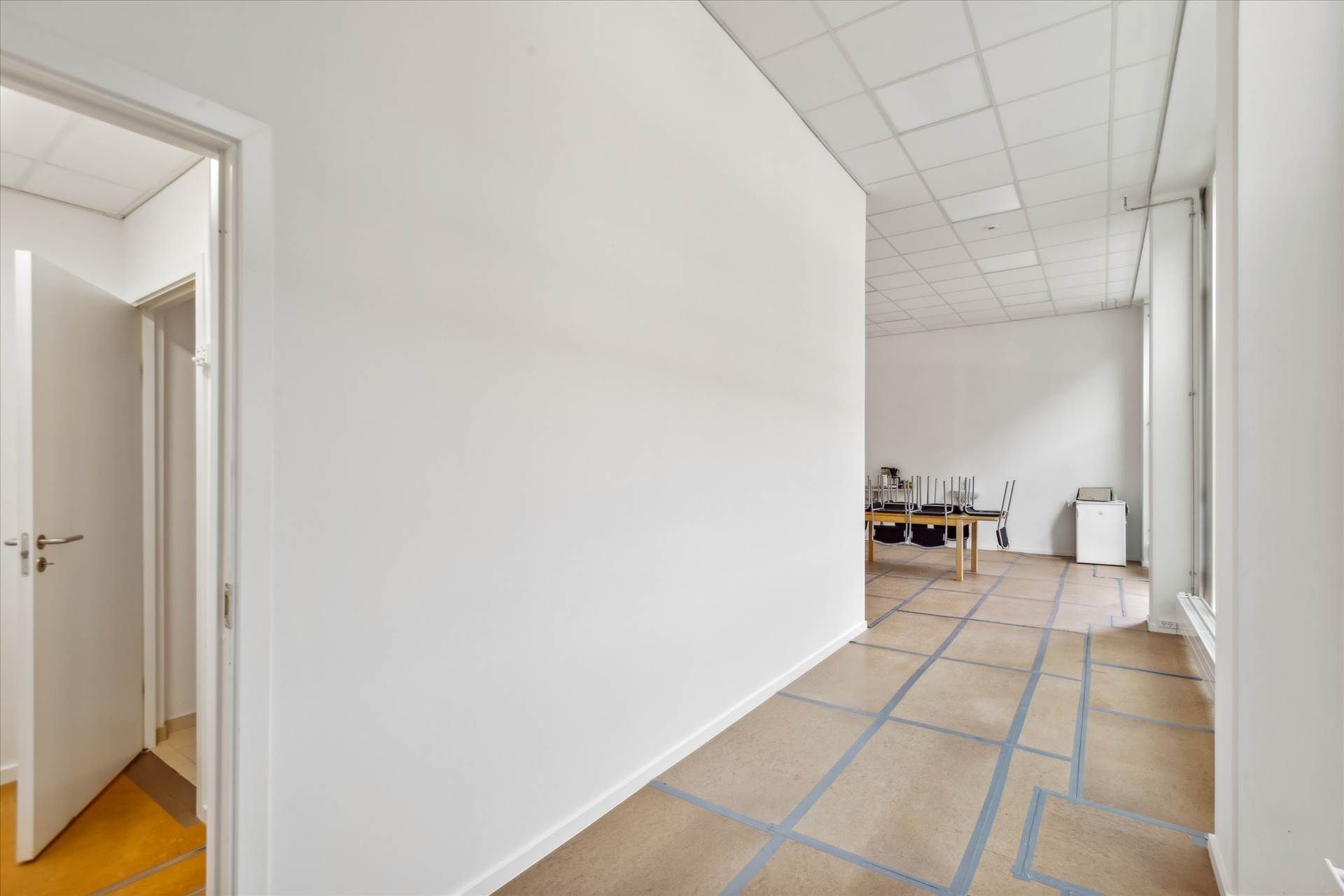 Lang lysegul gang, med hvide vægge og gulv, der er i gang med at blive udstykket til nyt gulv.