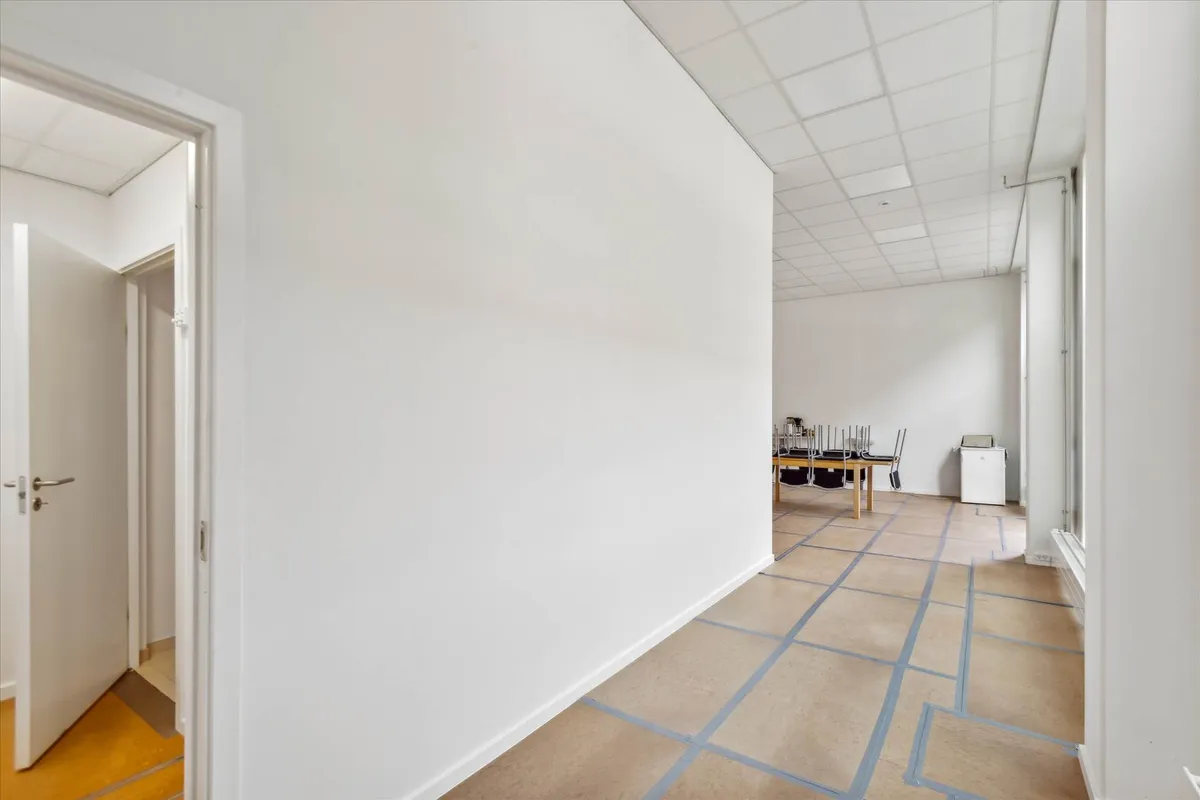 Lang lysegul gang, med hvide vægge og gulv, der er i gang med at blive udstykket til nyt gulv.