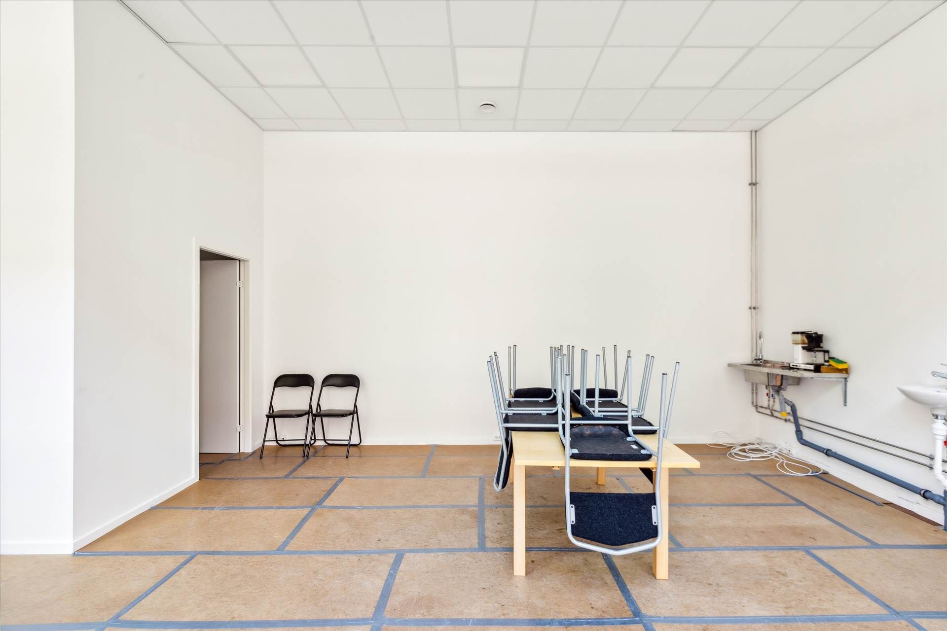 Foto af to stole, to stolhynder og et bord i en hvid stue. Væggene er hvide og gulvet er brungul og nyrenoveret.