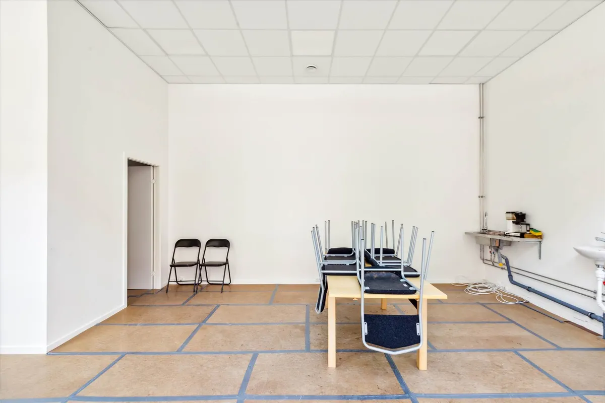 Foto af to stole, to stolhynder og et bord i en hvid stue. Væggene er hvide og gulvet er brungul og nyrenoveret.