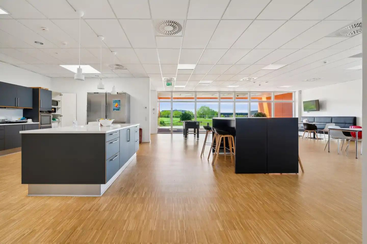 Store lyse lokaler med lysegult gulv, hvide vægge og loft, møbler og udstyr samt vinduer og døre