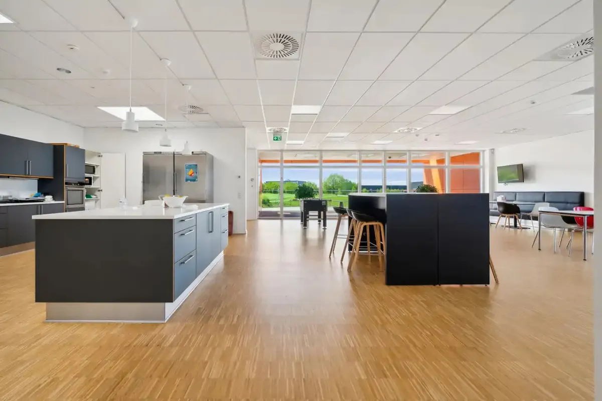 Store lyse lokaler med lysegult gulv, hvide vægge og loft, møbler og udstyr samt vinduer og døre