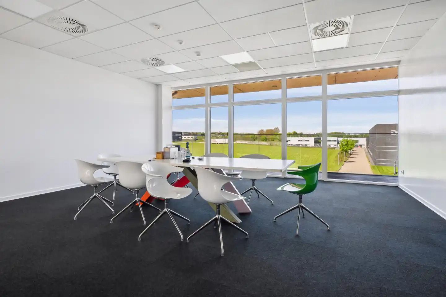 En konferencesal med hvide vægge og sort gulv samt møbler og vinduer i det lyse rum