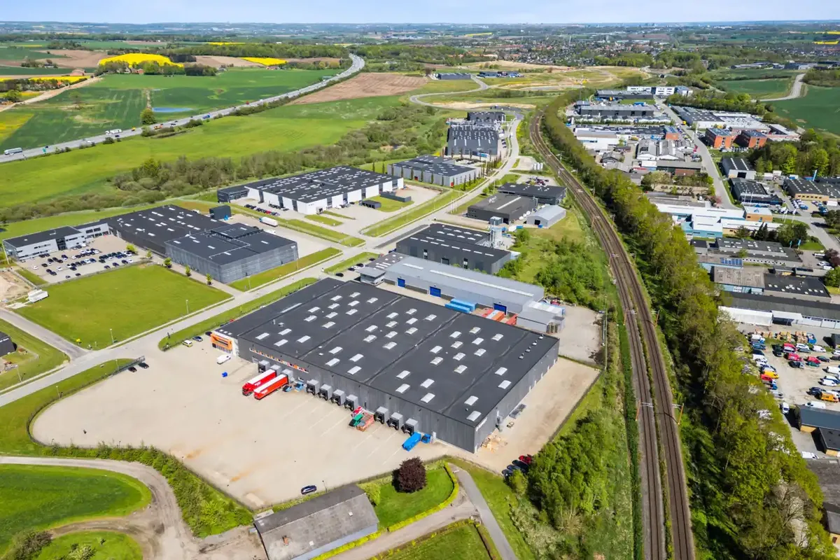 Luftfoto af et stort industriområde med store bygninger og flere parkerede lastbiler
