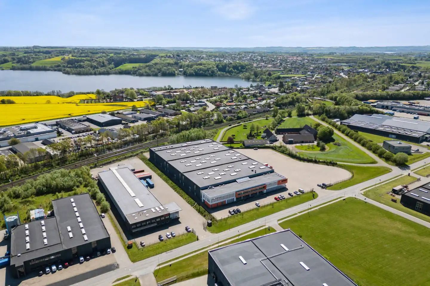 Stort industrikompleks med en stor parkeringsplads og mange biler parkeret rundt omkring