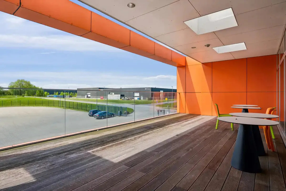 Terrasse med møbler og udsigt til parkeringsplads og bygninger med solpaneler på taget