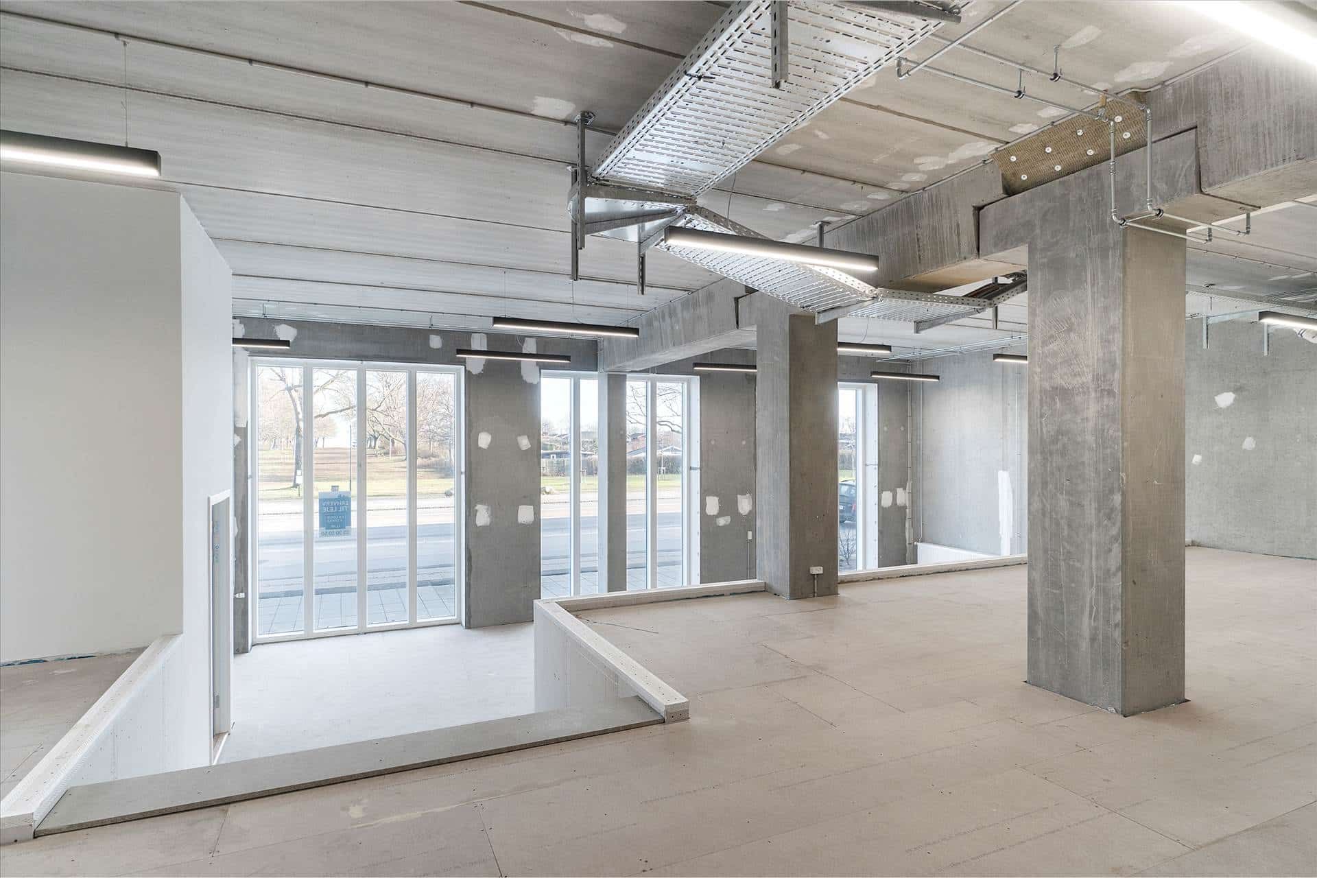 Store erhvervslokaler i Amager Strandvej med vinduer og indgang til gade, søjler og loftsbelysning i et byggeprojekt