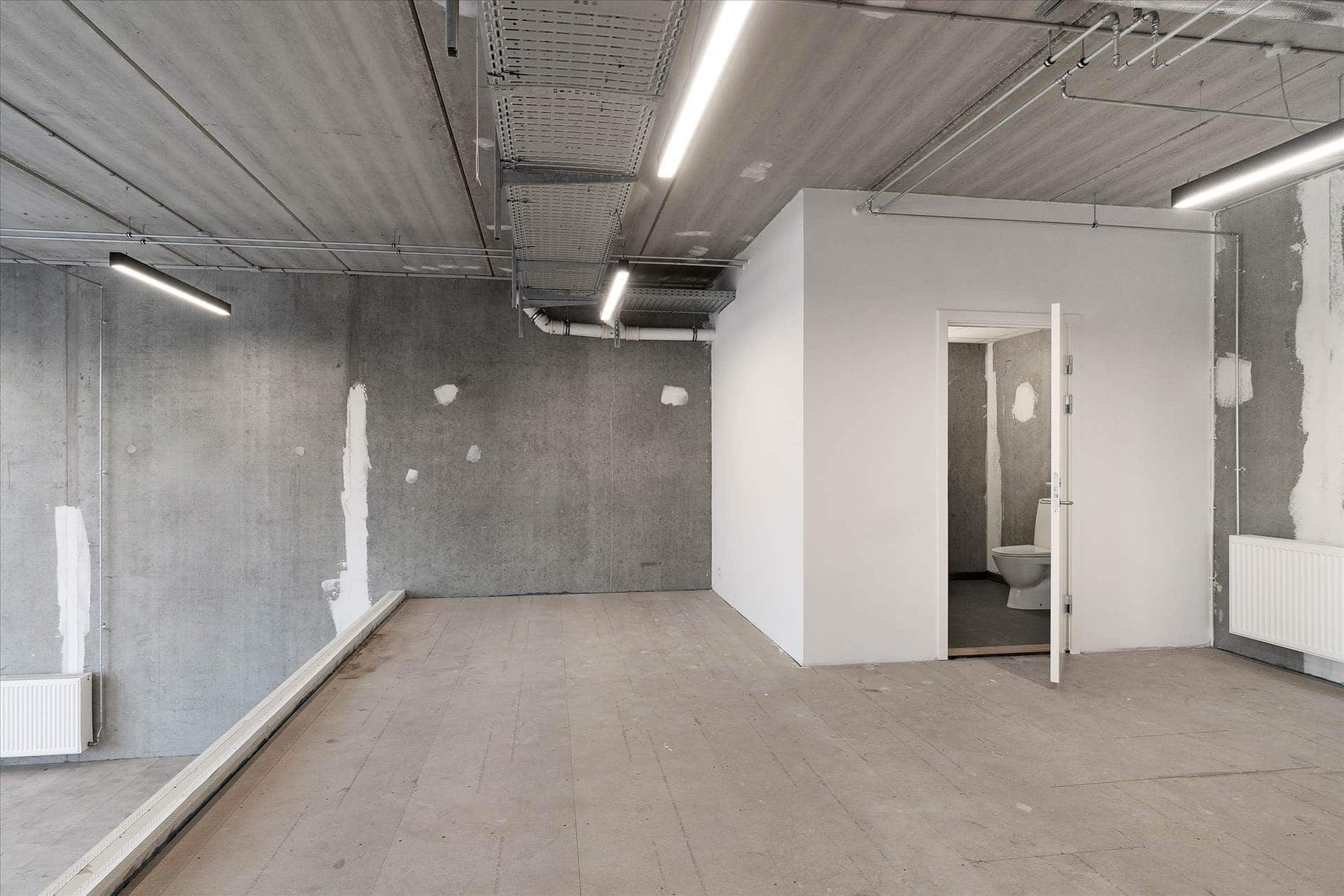 Store erhvervslokaler med højt til loftet og åbne vægge samt nyt toilet og radiatorer tilbehøret