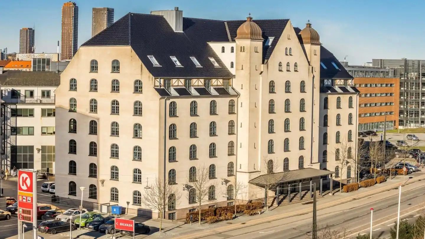 Kontorbyggeri med flere vinduer og facader af lys mursten og gulfarvet puds