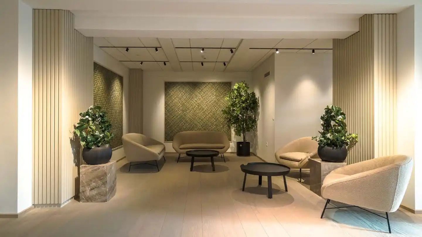 Kontorlokaler med højkvalitets møbler og indretning og masser af grønne planter i en elegant og velplejet stue