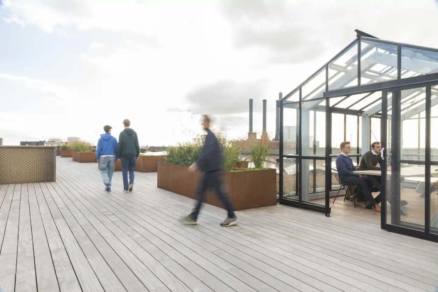 Personer vandrer på en træterrasse og holder samtale med hinanden. Et gulv udgør en af scenens hovedtemaer.