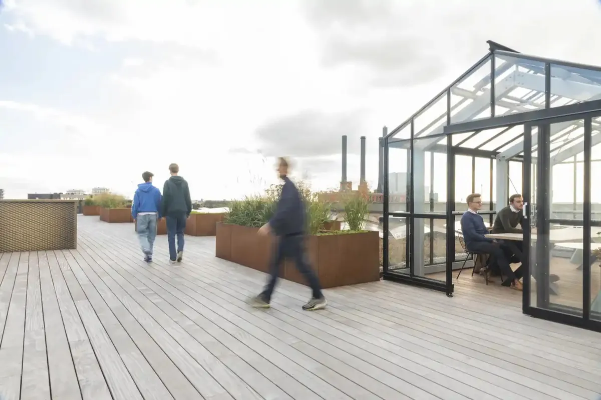 Personer vandrer på en træterrasse og holder samtale med hinanden. Et gulv udgør en af scenens hovedtemaer.