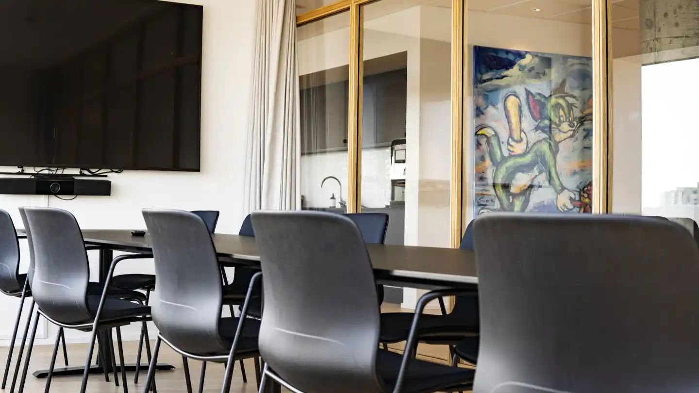 Kontorlokaler med moderne møbler og kunstværk. Store glasruder og højloftede rum. Fladt bord med flere sæder og en stor