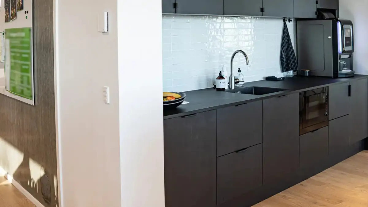 Sort og hvid køkken med lysegule og hvide fliser, moderne og minimalistisk design med sort granit og hængende kaffemaskine