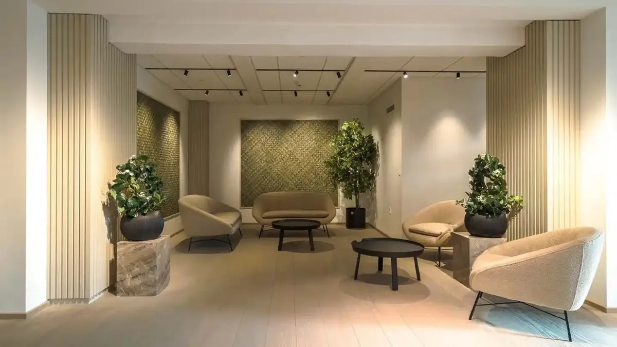 Kontorlokaler med beige læderstole og stol, trægulve og moderne design med tre høje lysekroner