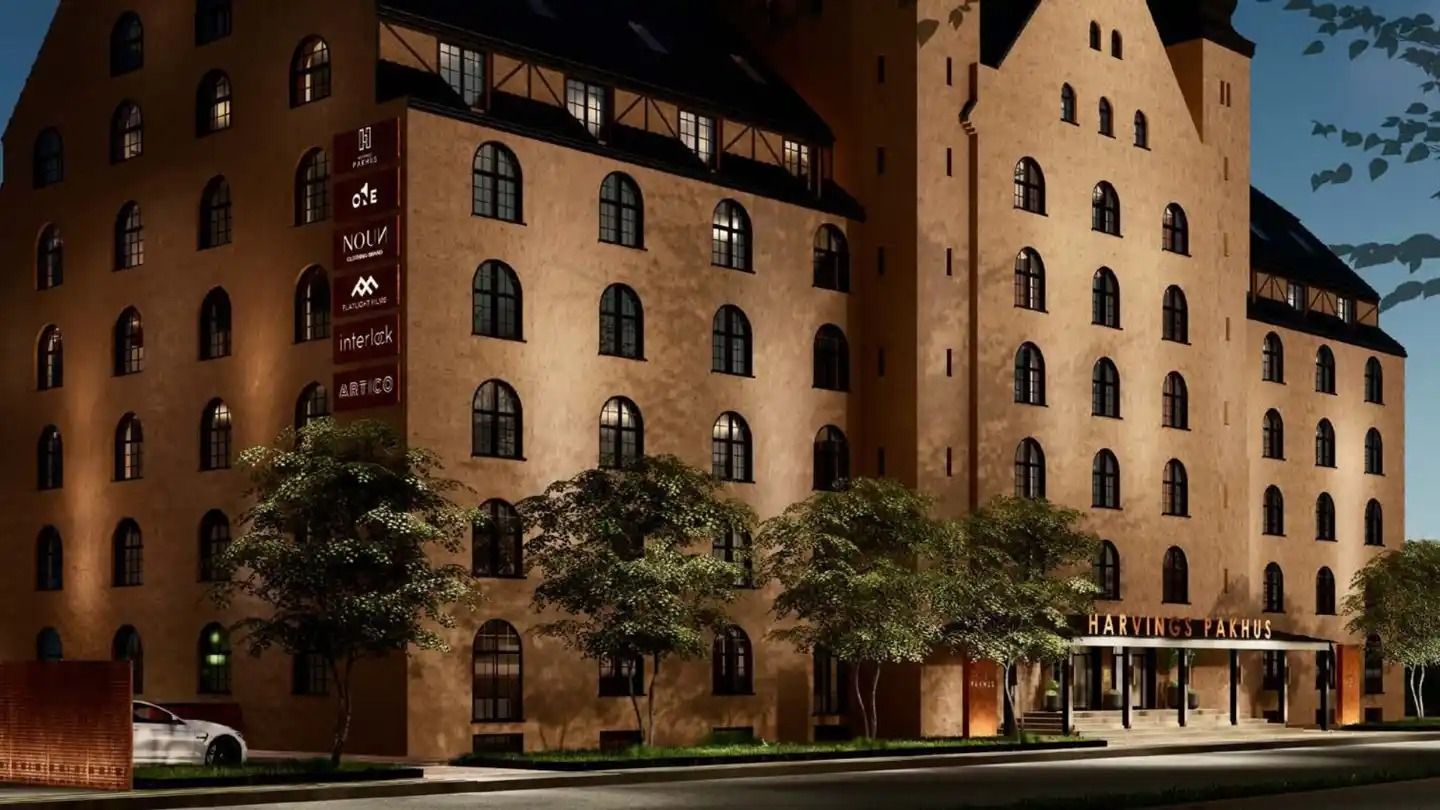 Moderne og elegant bygning med mange vinduer, navnet Harvings Pakhus og en hvid bil parkeret i forgrunden