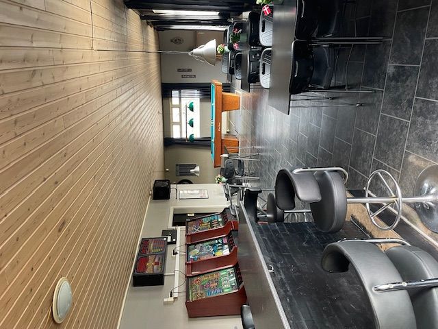 Spillehal med poolbord og spilleautomater samt møbler og lysekrone i gulvtæppet rum med træpaneler og vinduer