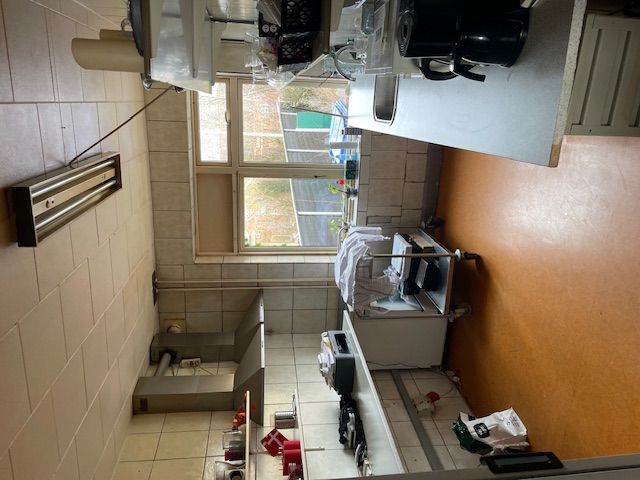 En stor komfur, ovn, arbejdsbord, skabe og andre husholdningsgenstande er placeret i en køkkenområde.