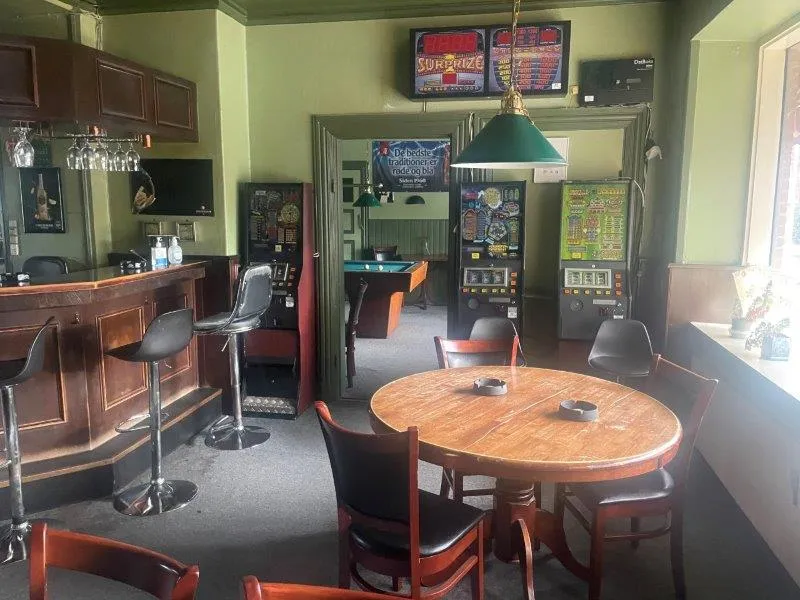 En værelse med møbler og indretning, der ligner en bar med et bord og stole samt en bardisk med en træskammel og flere