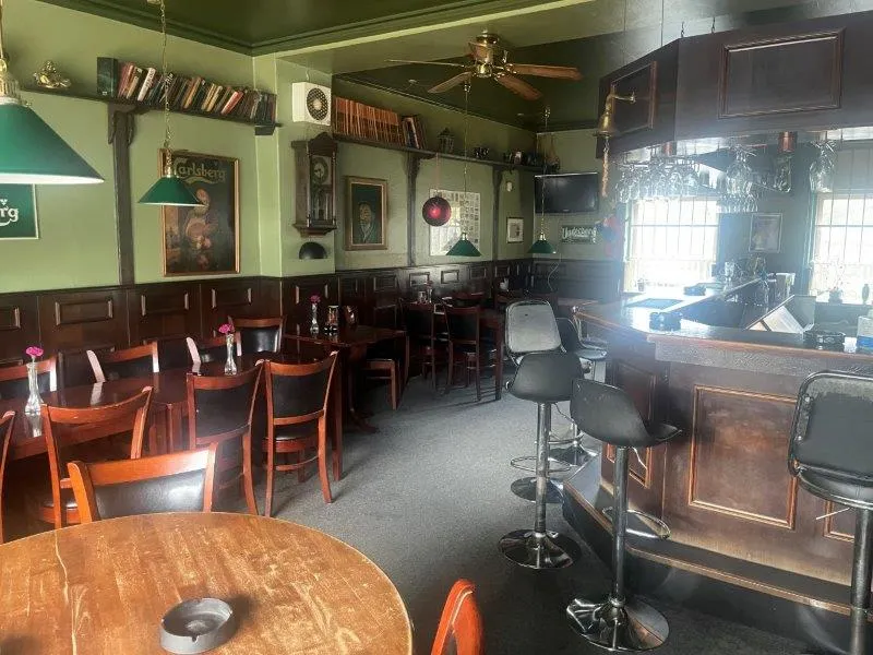 En lukket restaurant med stolpe og stolpe. Der er borde med stole og lysekroner. Der er en bar med høje stole og en TV-skærm.