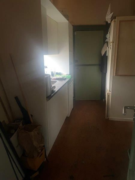 Lejlighed med køkken, komfur, ovn, spiseplads, skabe og indgang til et værelse med dør og vindueslys