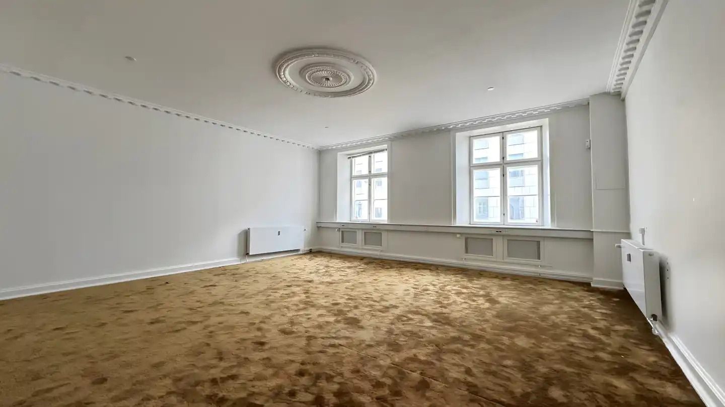 Kontorlokaler med højt til loftet og tavler, hvor der er højt gulv og hvide vægge