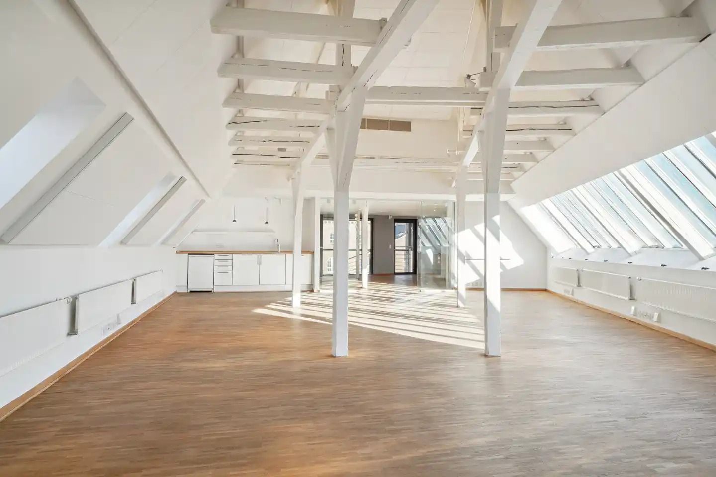 Lyst rum med lyse trægulve og loft. Høje vinduer giver masser af lys og udsigt til byen.