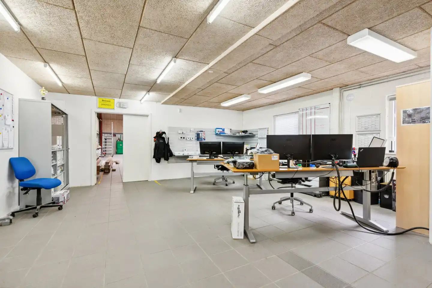 Kontor med to borde, to skærme, to skriveborde og to stolpe.