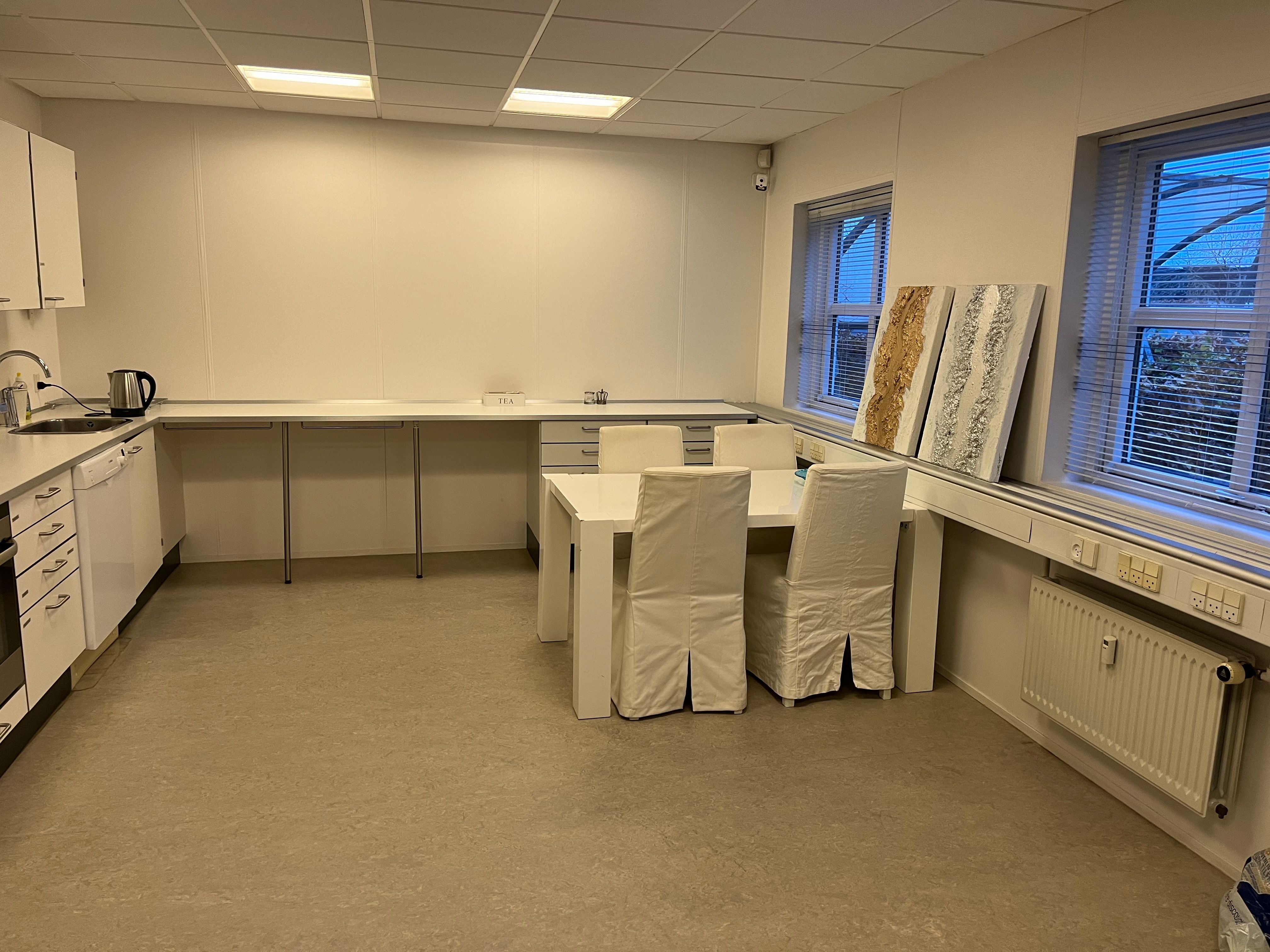 To tomme stole med hvide dæk og et bord udenfor et køkken med hvide vægge og gulv