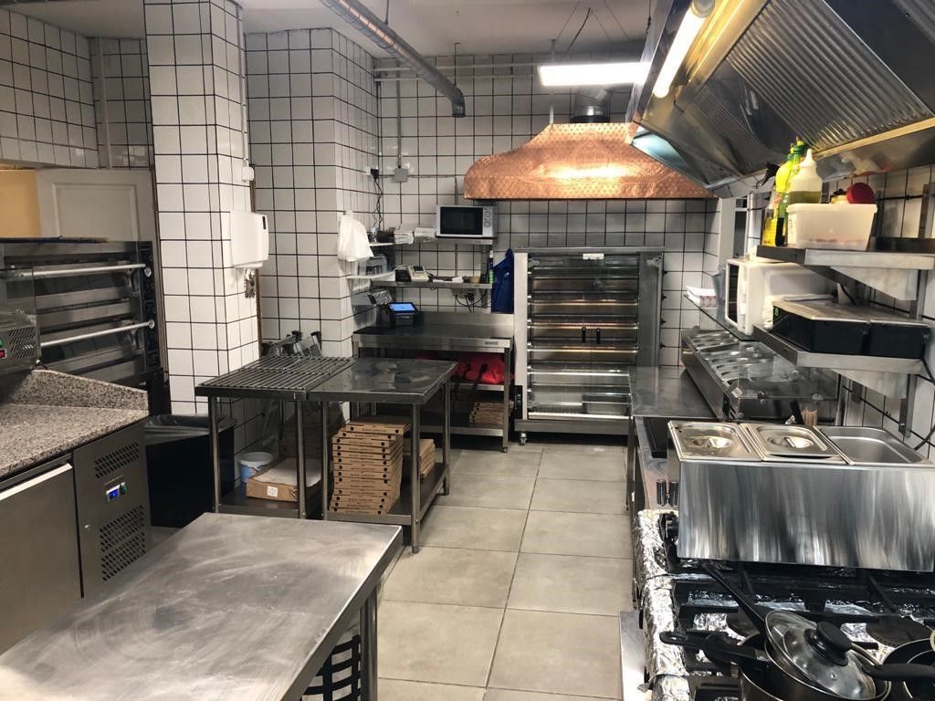 En moderne, ren og fuldt udstyret cateringskøkken med to kogeapparater, ovne, arbejdsborde og køleskabe.