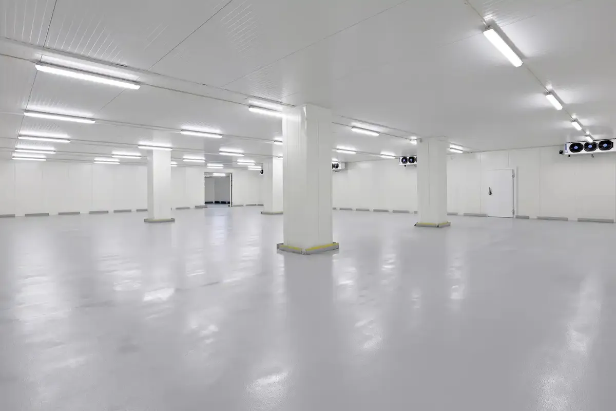 Lagerlejemål med kølefaciliteter, store hvide søjler og hvide vægge, lyse gulve og store vinduer med rulleskærme