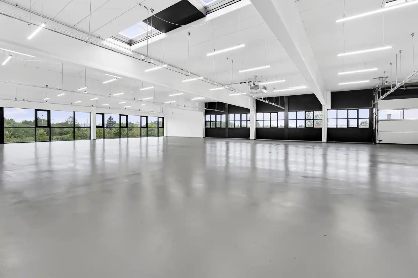 Rummelig og præsentabel kontor med hvide vægge, højt loft, store vinduer og moderne teknologi.