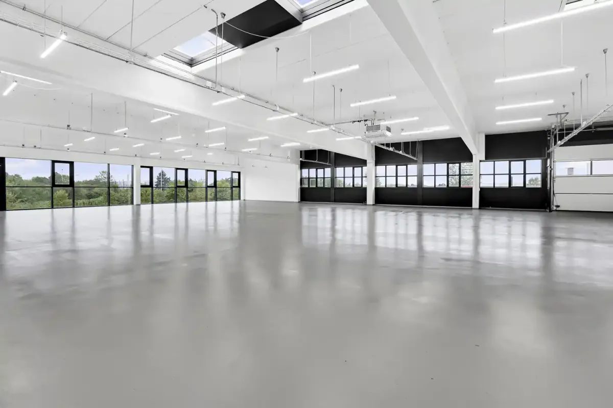 Rummelig og præsentabel kontor med hvide vægge, højt loft, store vinduer og moderne teknologi.